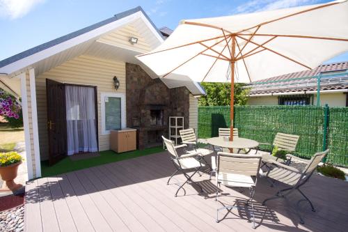 eine Terrasse mit Tisch, Stühlen und Sonnenschirm in der Unterkunft Aurada in Palanga