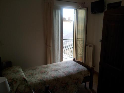 a bedroom with a bed and a window with a balcony at Locanda Bell'Aria in Uscio