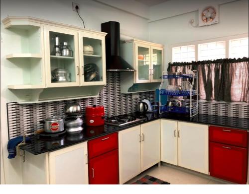- une cuisine avec des placards blancs et rouges et une cuisinière dans l'établissement EN Jays Residency (Service Apartments), à Kottayam