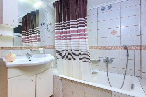 a bathroom with a sink and a tub and a shower at Villa Skala Marion (Michalis) in Skala Marion