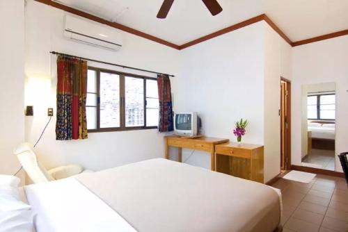 a bedroom with a white bed and a desk and window at Buakao Inn in Thong Sala