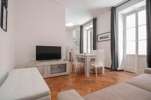 a white living room with a table and a tv at Bellagio Apartment in Bellagio