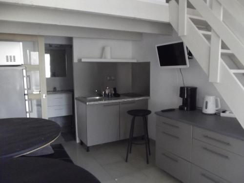 une cuisine avec un évier et un comptoir avec un tabouret dans l'établissement 67 Rue des Manilles, au Grau-du-Roi