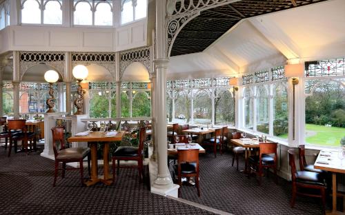 a dining room with tables and chairs and windows at Macdonald Kilhey Court Hotel in Wigan