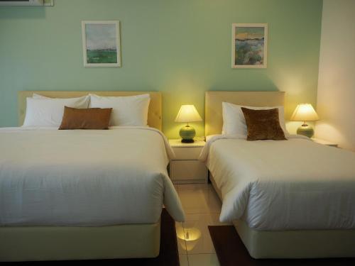 Cosy Studio Shah Alam في شاه عالم: سريرين في غرفة الفندق مع مصباحين