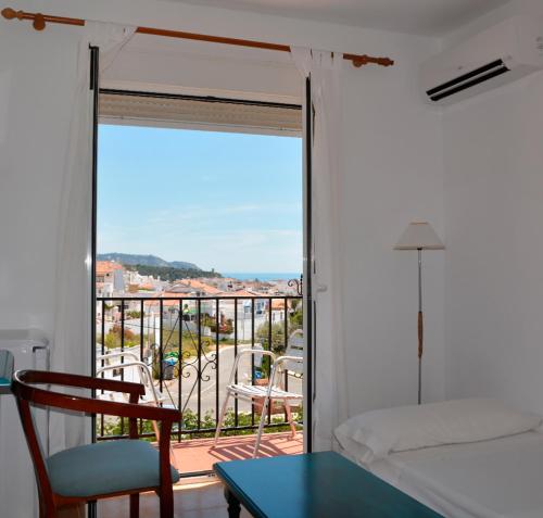 a bedroom with a balcony with a bed and a table at Hotel Al-Andalus in Nerja