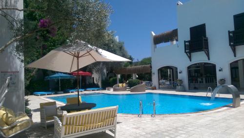 a swimming pool with an umbrella and chairs and a table at ece "vegan"hotel Bodrum in Golturkbuku