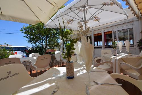 
a dining room table with chairs and umbrellas at Hotel Al-Andalus in Nerja
