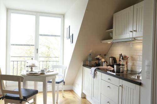a kitchen with white cabinets and a table and a window at von Deska Townhouses - White House in Hamburg