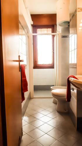 a bathroom with a toilet and a sink and a window at Condominio Moschettieri in Bibione