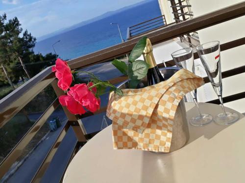 - une table avec des verres à vin et des fleurs sur le balcon dans l'établissement Maya Bay, à Kallithéa Halkidikis