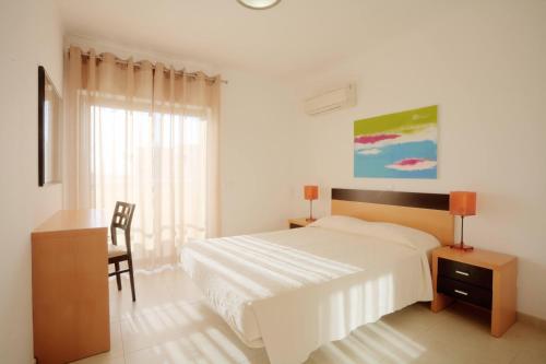 - une chambre blanche avec un lit, un bureau et une fenêtre dans l'établissement Areias da Rocha by amcf, à Portimão