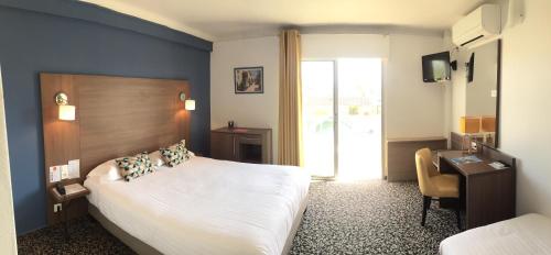 a hotel room with a large bed and a desk at Le Galion Hotel et Restaurant Canet Plage - Logis in Canet-en-Roussillon