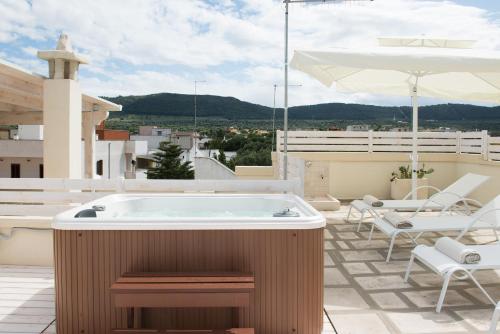 a hot tub on a patio with chairs and an umbrella at Antica Via Roma B&B E RELAX in Montalbano