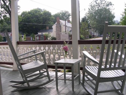 two chairs and a table with a vase of flowers on a porch at Hopkins Ordinary Bed, Breakfast and Ale Works in Sperryville