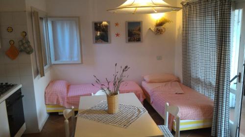 a small room with two beds and a table at Casa Gialla in Costa Paradiso