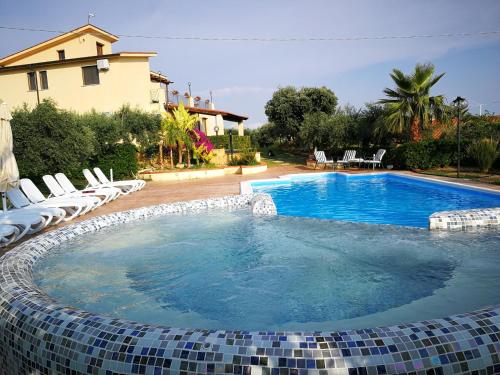 a swimming pool with chairs and a house at B&B Le Foglie D'Argento in Caltabellotta