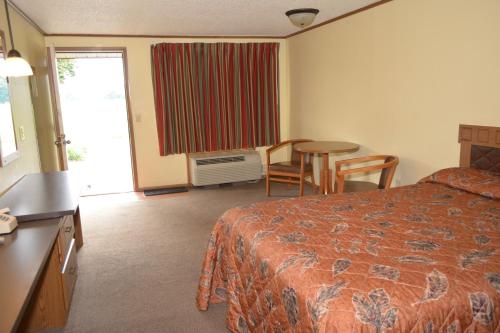 a hotel room with a bed and a table and chairs at Arbor Inn of Historic Marshall in Marshall