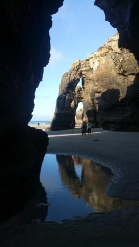 een groep mensen die op een strand lopen met een grot bij Apartamento Costa de Lugo in Foro