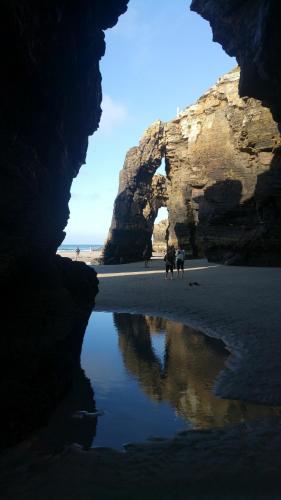 a group of people walking on a beach with a cave at Apartamento Costa de Lugo in Foro