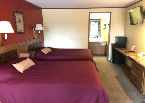 two beds in a hotel room with purple sheets at Arbor Inn of Historic Marshall in Marshall