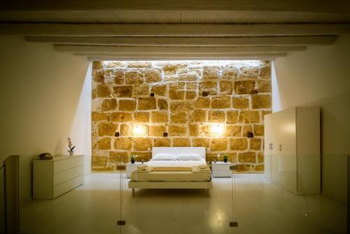 a bedroom with a bed in front of a stone wall at LA CARRETTERIA, ospitalità siciliana in Avola