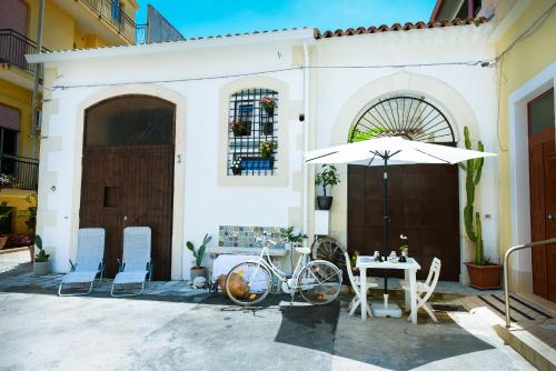 a white house with a bicycle and an umbrella at LA CARRETTERIA, ospitalità siciliana in Avola