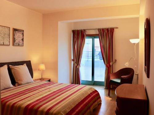 a bedroom with a bed and a chair and a window at Algarve Sweet Home - Marina Front in Albufeira