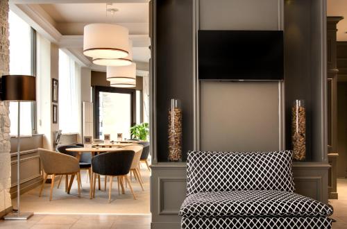 a living room with a chair and a table at Hôtel des Ducs in Dijon
