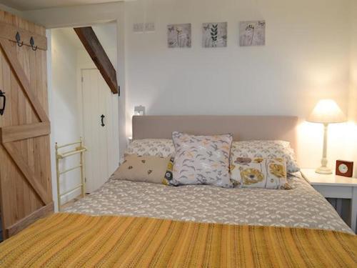 een slaapkamer met een bed met kussens erop bij Swallow Barn in Llanwrtyd Wells