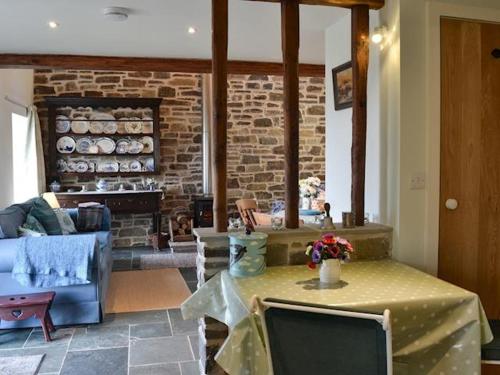 a living room with a table and a brick fireplace at Swallow Barn in Llanwrtyd Wells