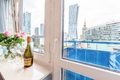 a bottle of wine sitting on a table in front of a window at Gold Apartment Złota - Palace of Culture View- NETFLIX-Free Parking 500 meters from the apartment in Warsaw
