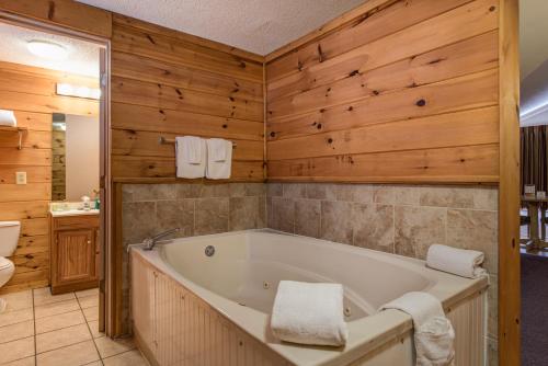 uma casa de banho com banheira e paredes de madeira em Green Valley Motel em Pigeon Forge