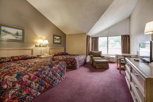 una camera d'albergo con due letti e una scrivania di Green Valley Motel a Pigeon Forge