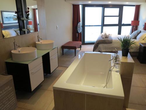 a bathroom with two sinks and a large tub at Beautiful Ocean Views in Strand