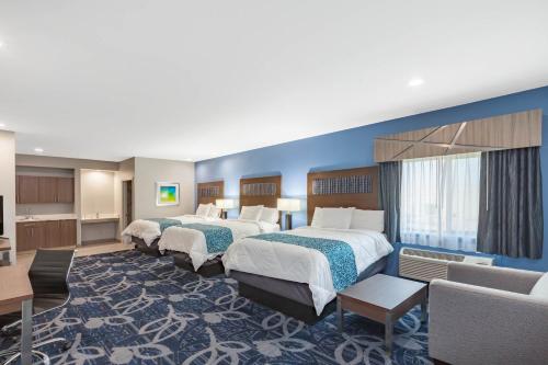 a hotel room with three beds and a couch at Baymont by Wyndham Houston Hobby Airport in Houston