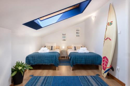 アヴェイロにあるFeeltheland Ria Residenceのベッド2台とサーフボードが備わる客室です。