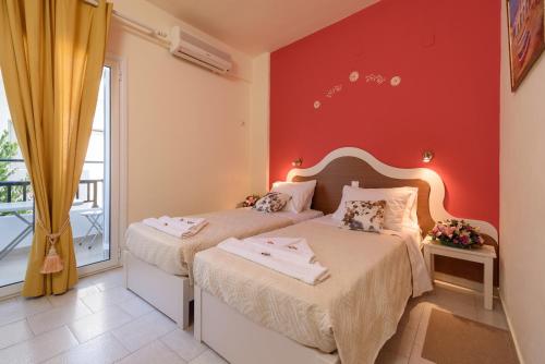 two beds in a bedroom with a red wall at Antigoni in Agia Galini