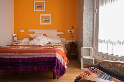 a bedroom with a bed with an orange wall at Balenax Pensión in Gijón