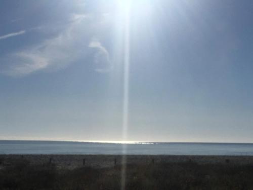 a beach with the sun shining on the water at Sa Murta Bianca Guesthouse in Budoni