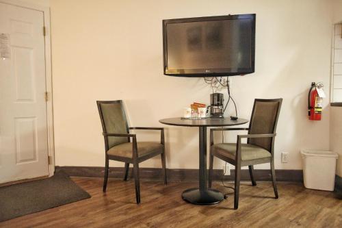 a table and chairs with a television on the wall at Best Budget Inn & Suites Kamloops in Kamloops