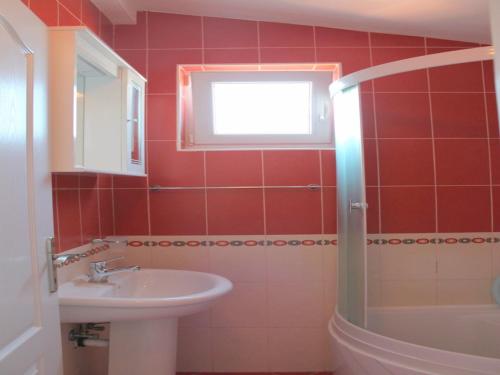 un bagno rosso con lavandino e finestra di Apartments Galija a Petrovac na Moru