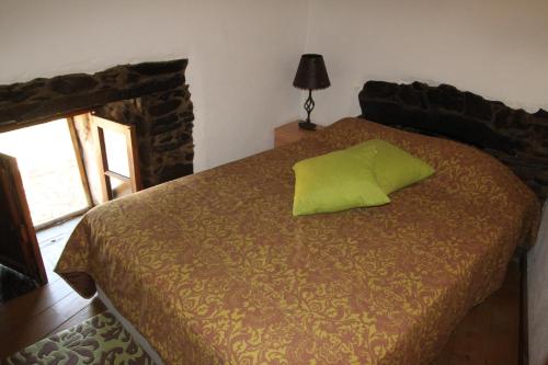 a bedroom with a green pillow on a bed at Aldeia Oliveiras in Sobreira Formosa