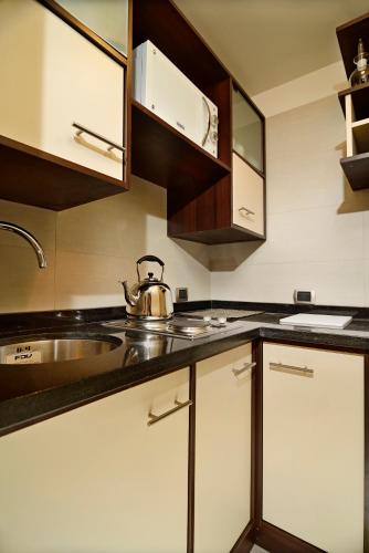 a kitchen with white cabinets and a tea kettle on the counter at Hotel Gran Palace in Santiago