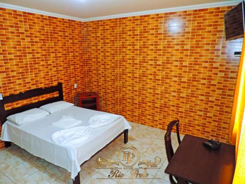 a bedroom with a bed and a table and a brick wall at Rio Preto Hotel in Formosa