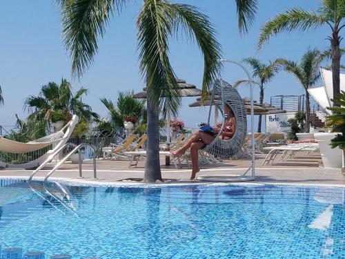 a woman is standing next to a swimming pool at Residence Porto Ulisse in Parghelia