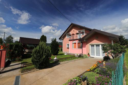 a pink house with a fence in a yard at Zlata Apartment in Fužine