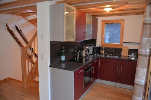 a kitchen with red cabinets and a sink at Chalet Truffer Ulrichen in Ulrichen