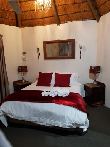 a bedroom with a large bed with red pillows at Piccadilly Farm Cottages in Lions River