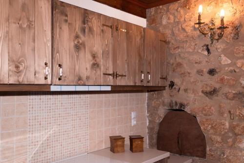 a kitchen with wooden cabinets and a stone wall at Mossiori Serai in Sitariá